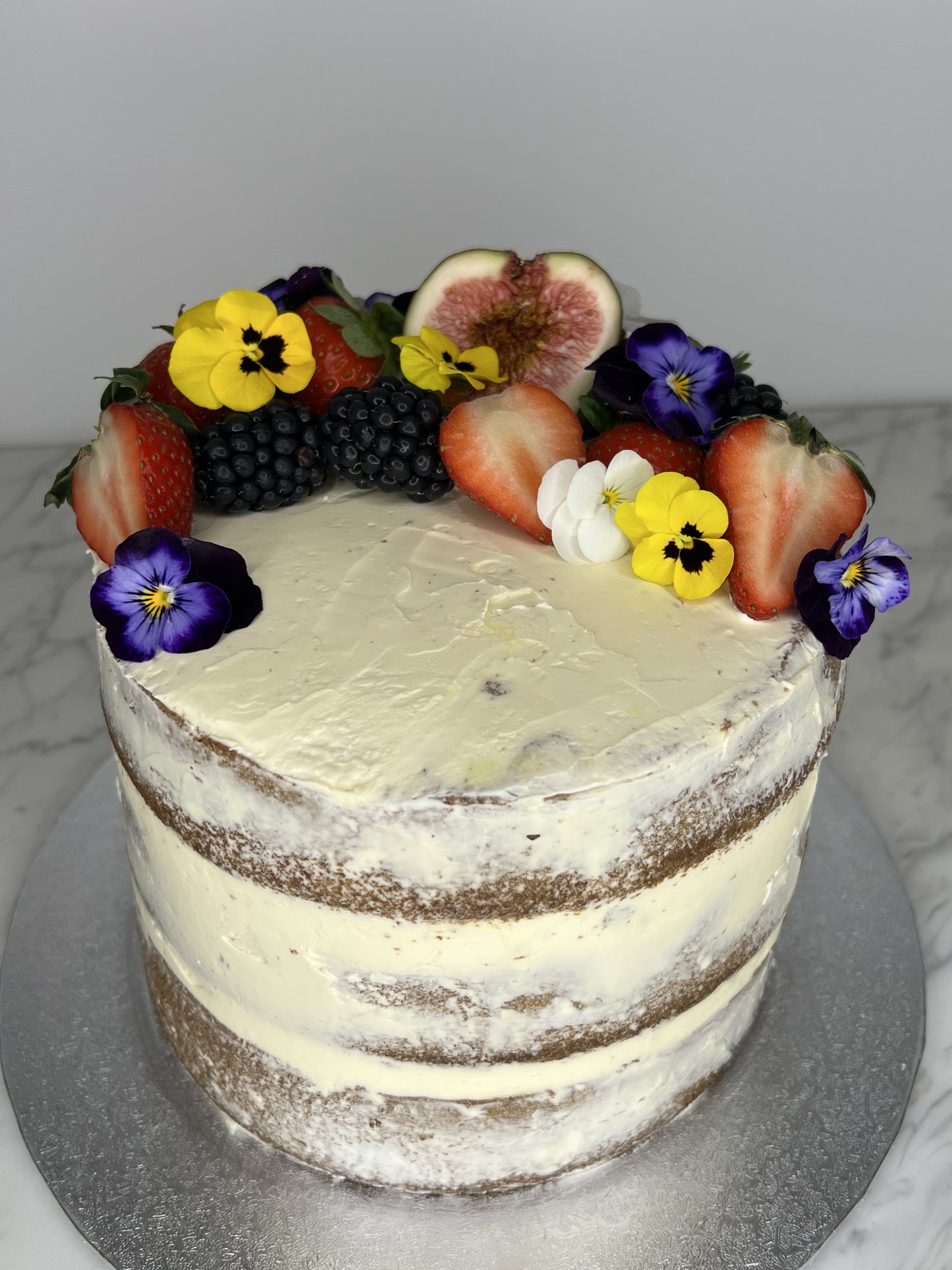 Naked cake with fruits and edible flowers